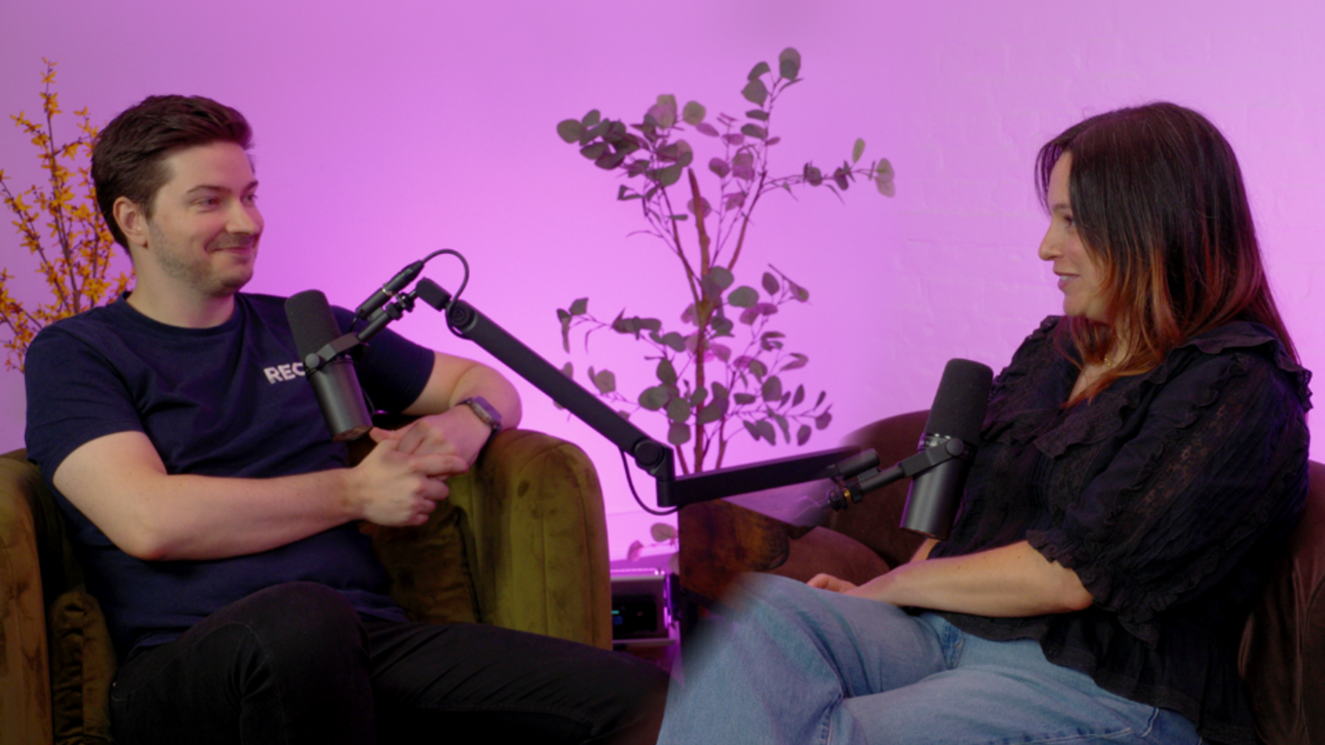 Matt Maidment of REO Digital and Sevrin Morris of Mr & Mrs Smith recording the Beyond Conversion podcast, seated on a sofa against a pink backdrop.